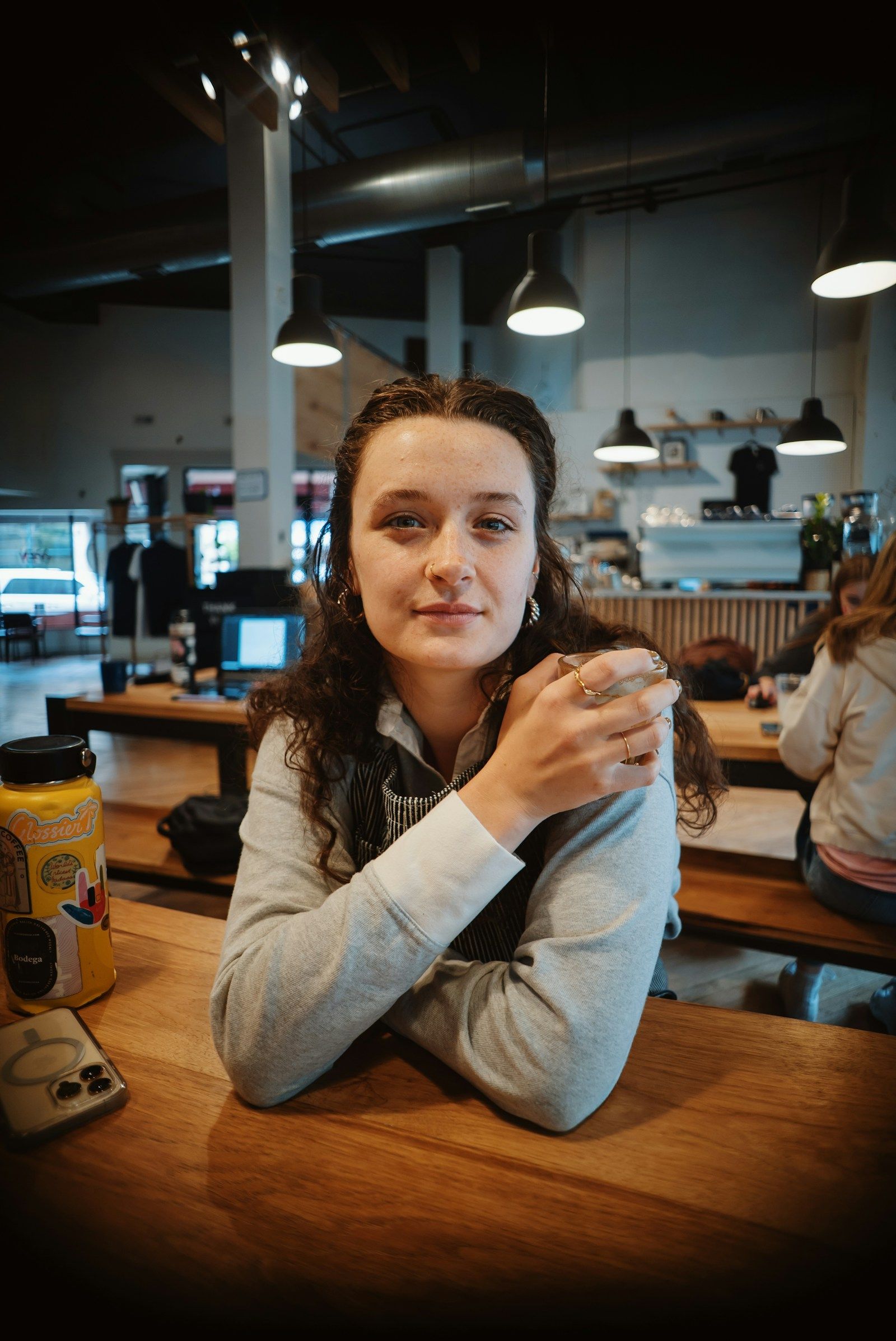 A woman on her own at a café table, smiling, holding a coffee