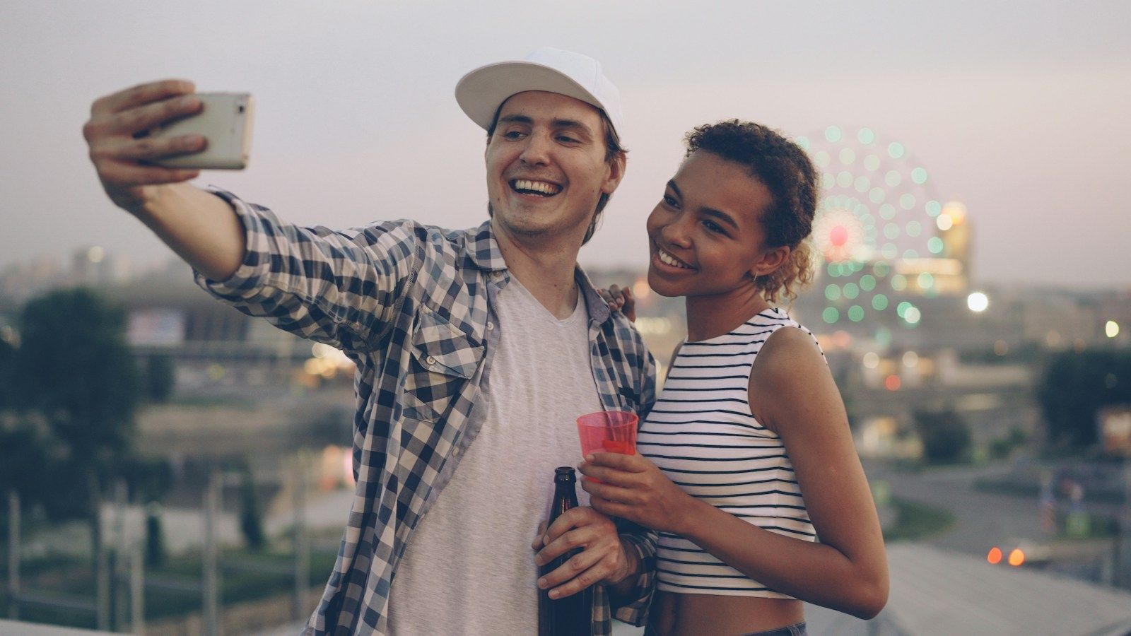 A couple taking a selfie with city lights behind them